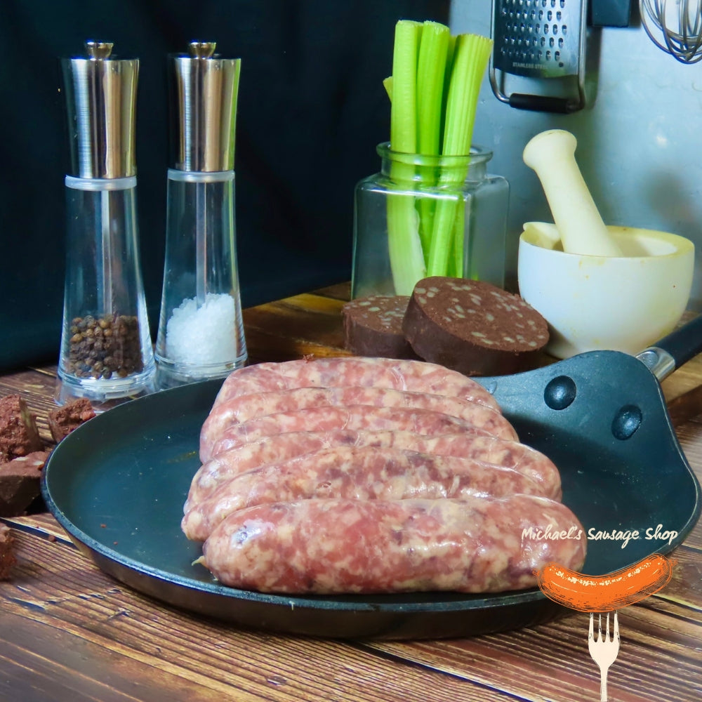 Raw Black Pig sausages on a pan with kitchen items in the background. Michael's Sausage Shop.