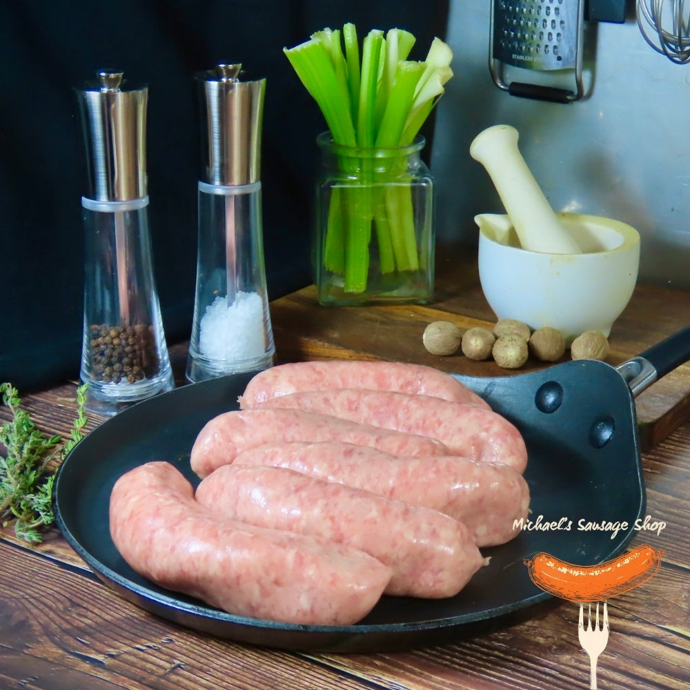 Raw classic plain pork sausages in a pan on a wooden table. By Michael's Sausage Shop.