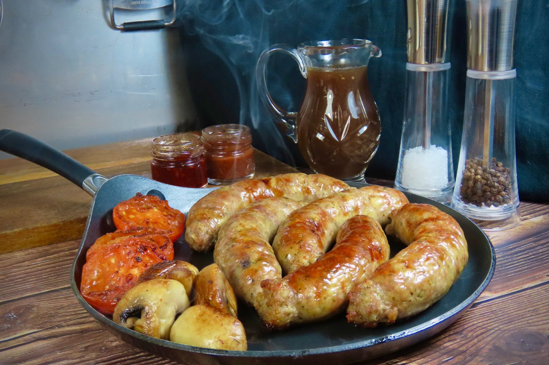 Skillet with sausages, and condiments on a wooden surface